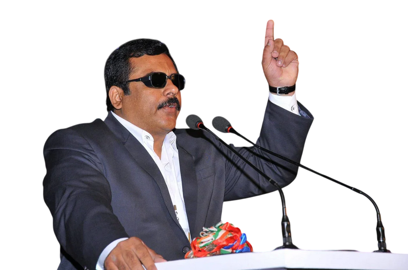Man in suit with sunglasses giving a speech at a podium, pointing upward
