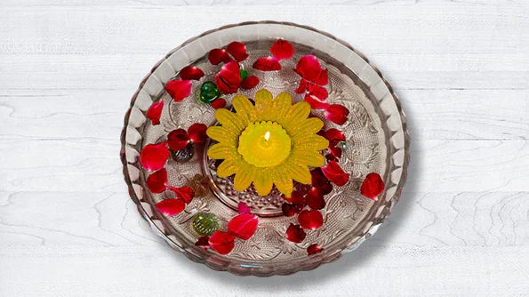 Yellow sunflower-shaped floating candle in glass bowl with rose petals